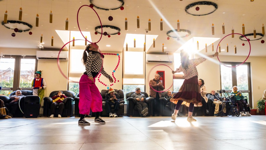 Artistas de circo con aros actuando para personas mayores en un centro comunitario.